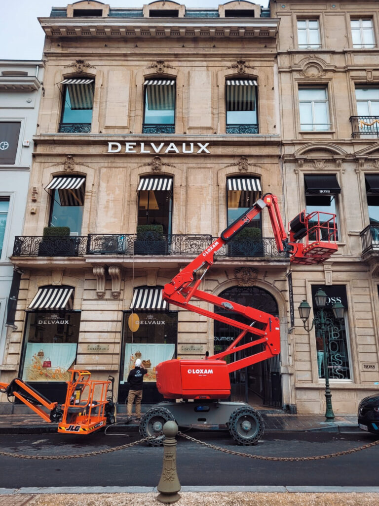 Nettoyage sur machine élevatrice sur grande façade avec protections solaires de la devanture de chez Delvaux